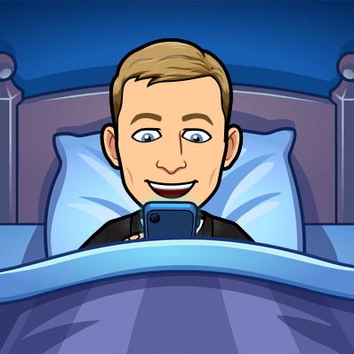 smiling while looking at cellphone while under the covers in bed