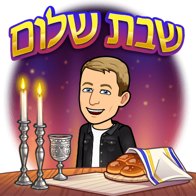 smiling next to a cup of wine lite candles and challah bread, shabbat shalom